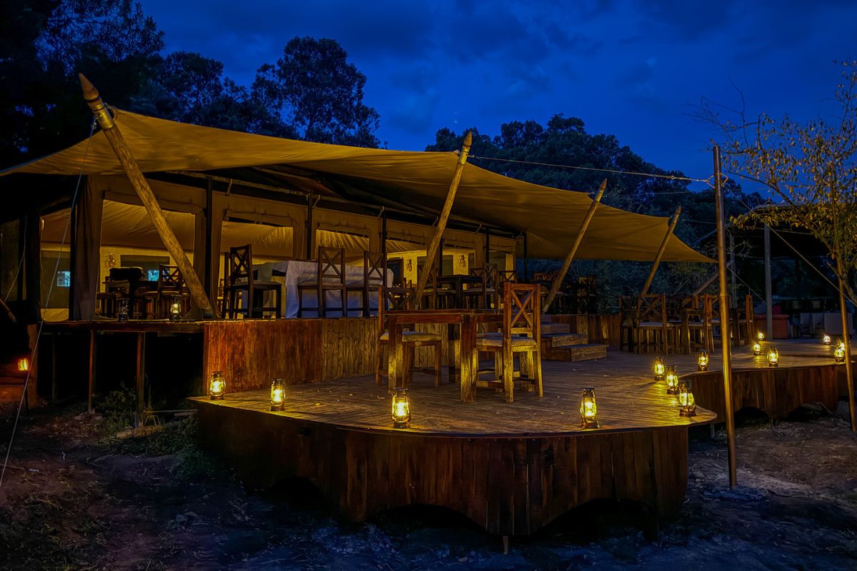 Lantern lit safari dining terrace at Ilora Retreats camp in the Masai Mara at night