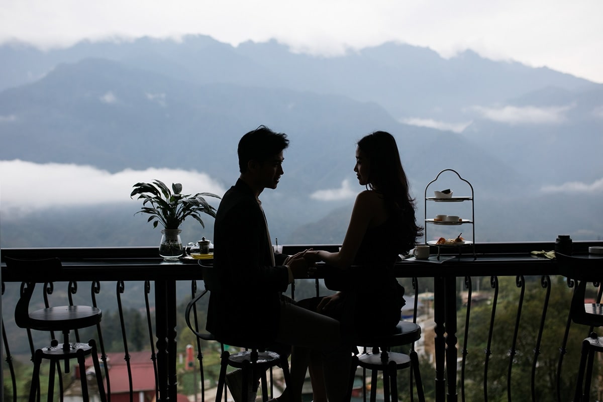 Couple sitting on the panorama terrace of DeLaSol Phat Linh Hotel Sapa overlooking the mountains