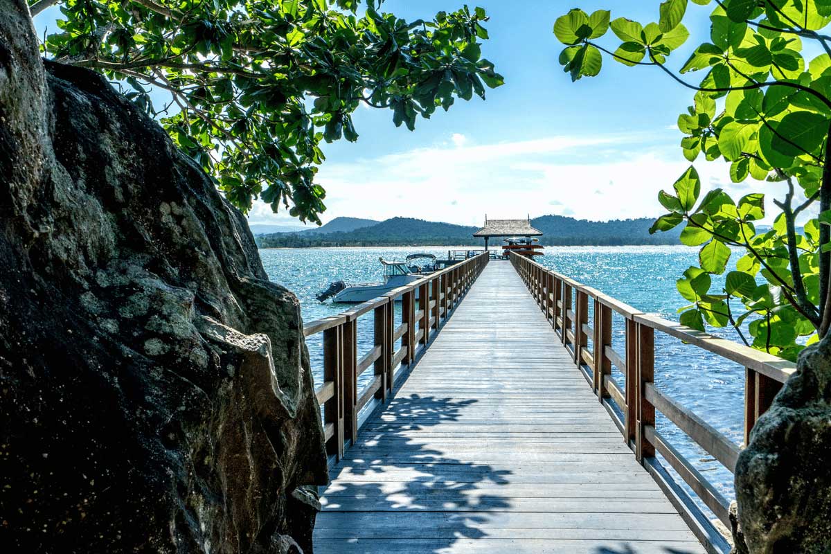 Wooden pier at Nam Nghi Coral Peninsula Phu Quoc Resort with boats on the sea