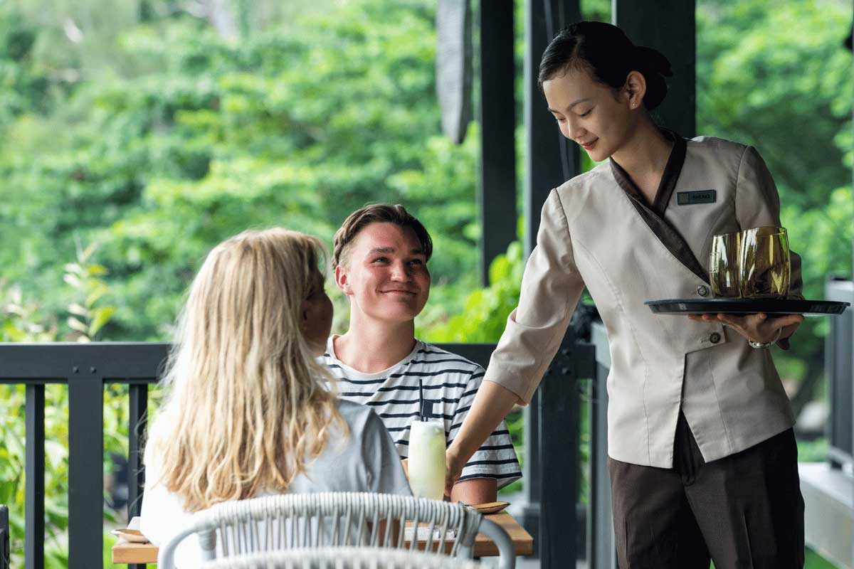 Staff member serving drinks to guests at the restaurant of Nam Nghi Coral Peninsula Phu Quoc Resort